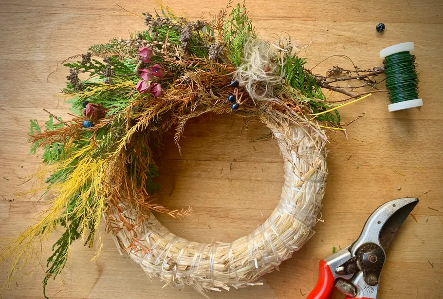 Decorated wreath on a wooden table, tools nearby.