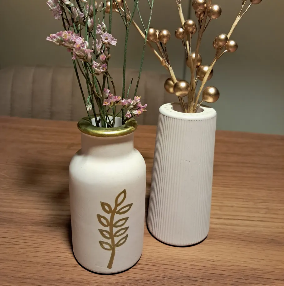 Zwei dekorative Vasen mit Blumen auf Tisch.