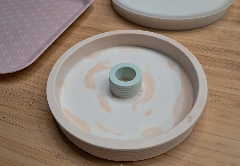 Candle mold with core on wooden surface.