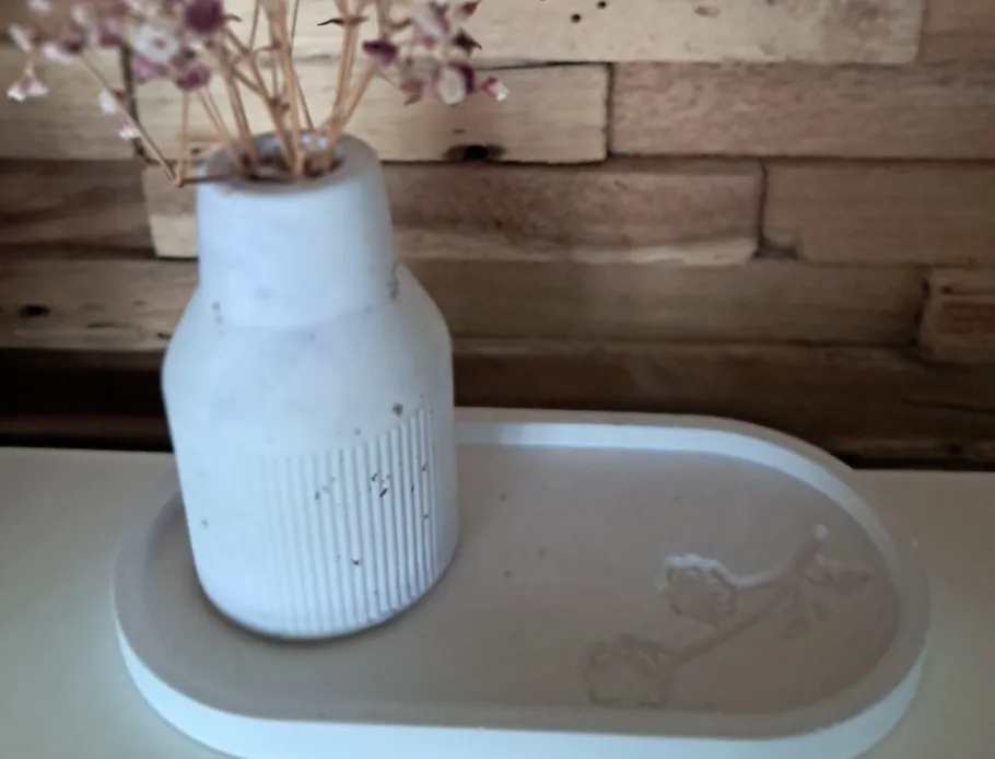 Weiße Vase mit Blumen vor Holzhintergrund.