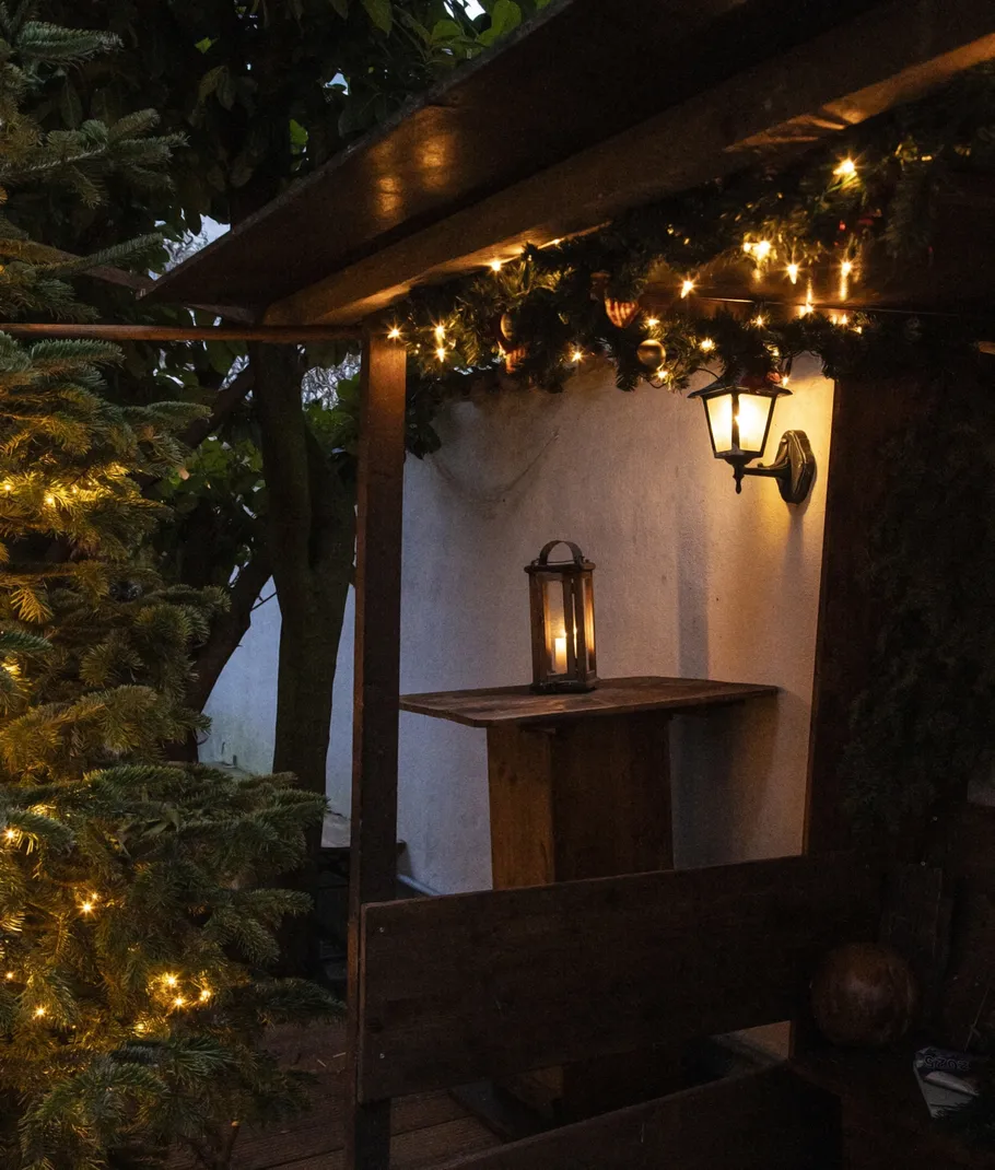 Lantern and fairy lights in cozy outdoor setting.