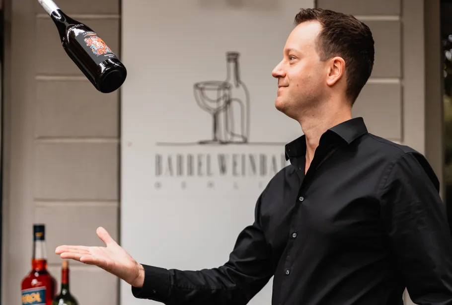 Man flipping bottle outside wine bar.