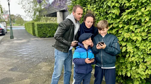 Family looking at smartphone near green bush.