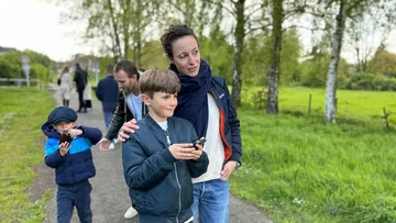 Familie spaziert draußen auf einem Parkweg.