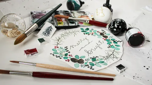 Art supplies and Christmas card on table.