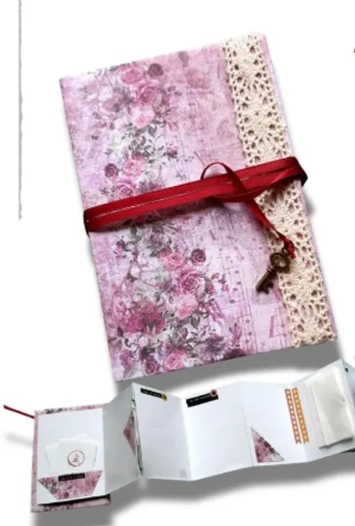 Floral pink scrapbook with red ribbon and key.
