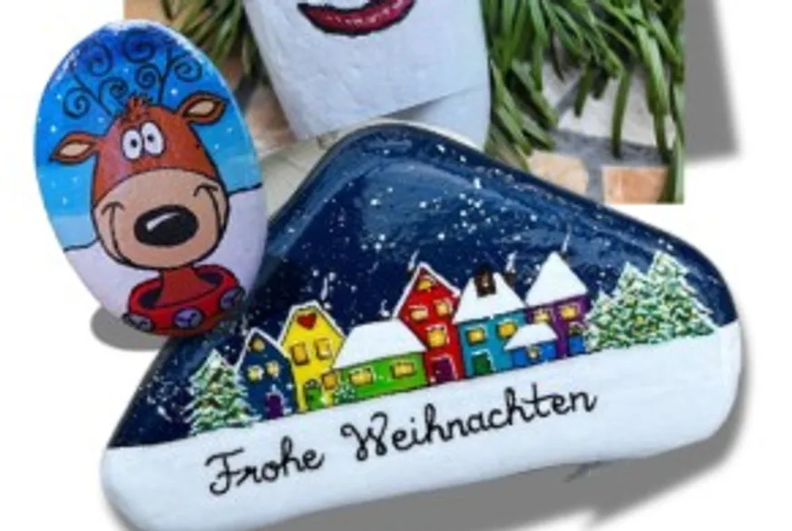 Bemalte Steine mit Rentier und Weihnachtsdorf.