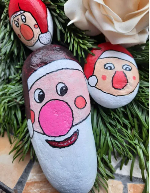 Bemalte Steine als Weihnachtsmann auf Laub.