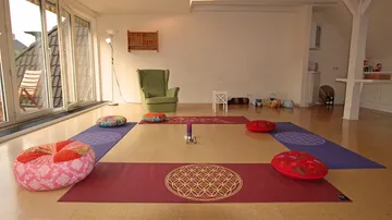 Meditationsraum mit Kissen und Matten im Raum.