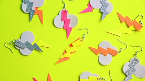 Colorful lightning bolt earrings on yellow background.