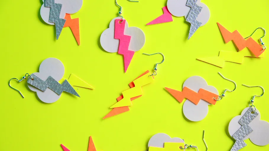 Colorful lightning bolt earrings on yellow background.