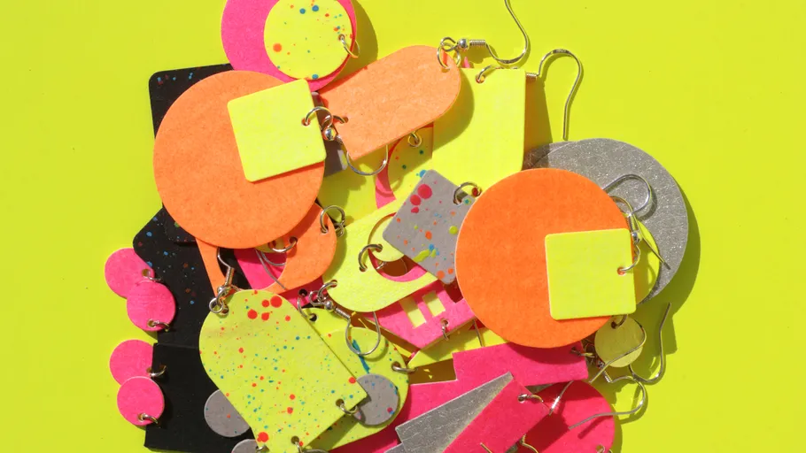 Colorful geometric earrings on yellow background.