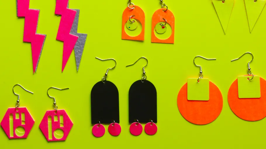 Colorful geometric earrings on green background.