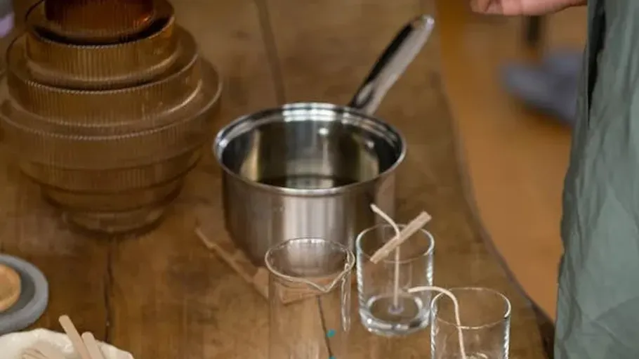 Candle-making setup with pot on wooden table.
