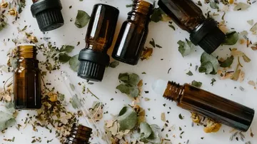 Brown bottles and dried herbs on white surface.