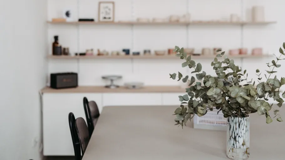Vase with green plant on dining table.
