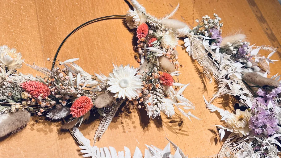 Blumenkranz mit Trockenblumen auf Tisch.