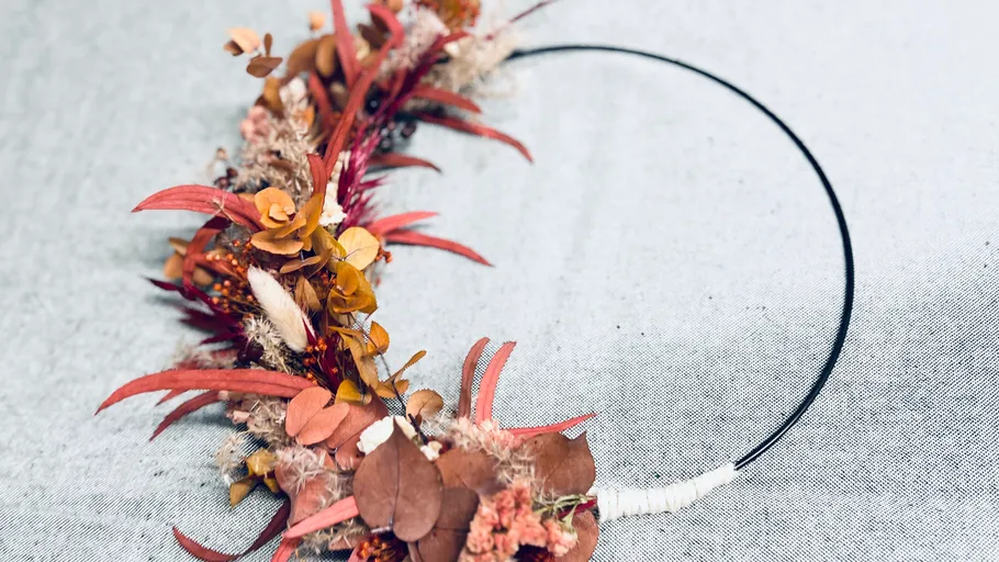 Herbstkranz mit Trockenblumen auf Tisch.