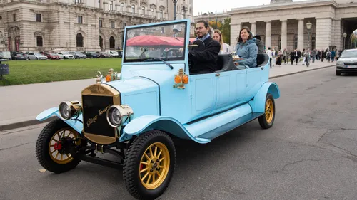 Blue vintage car driving on city street.