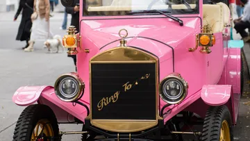 Pink vintage car parked on street.