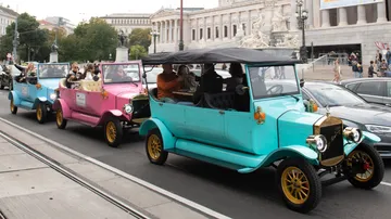 Colorful vintage cars driving on city street.