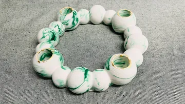 Green-white circular ceramic sculpture on fabric.