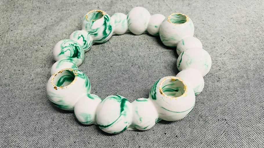 Green-white circular ceramic sculpture on fabric.