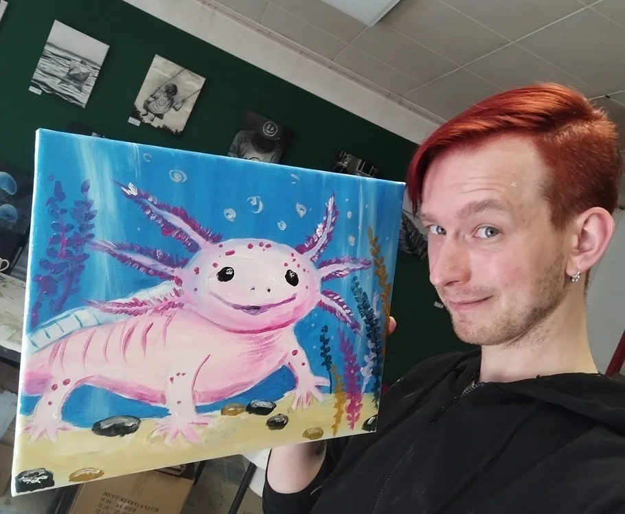 Person holding axolotl painting in art studio.