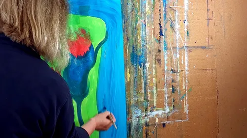 Artist painting abstract art on large canvas.