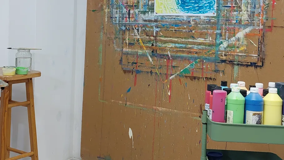 Art studio with paint bottles and easel.