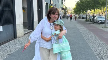 Woman and child hugging on city street.