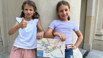 Zwei lächelnde Mädchen halten eine Stadtkarte.