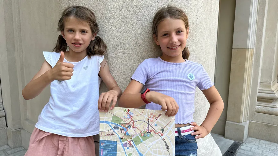 Two girls holding a city map outside a building.
