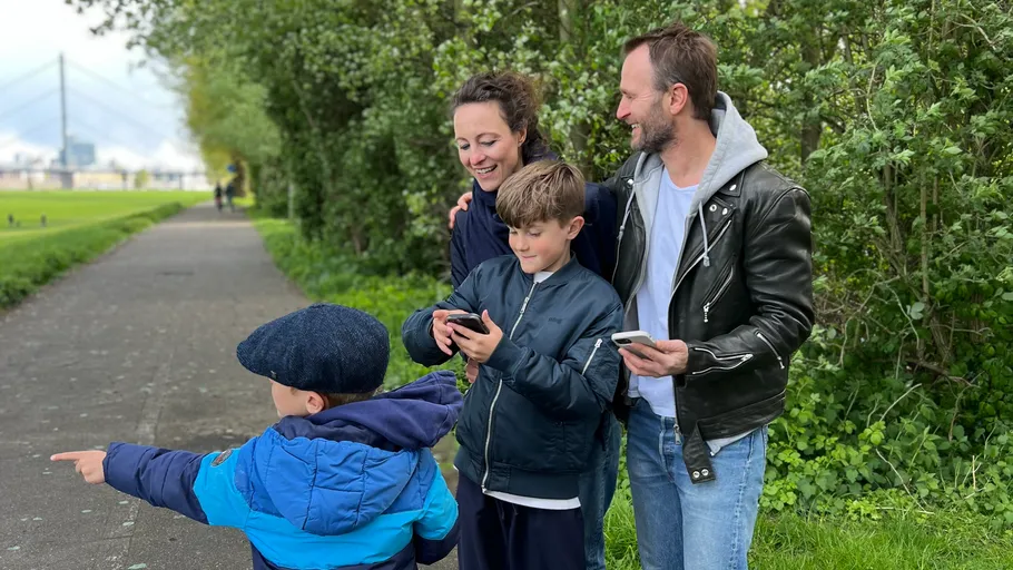 Familie nutzt Telefone im Freien, Junge zeigt.