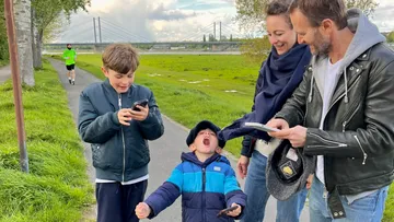 Familie mit Handys auf einem Flussweg.