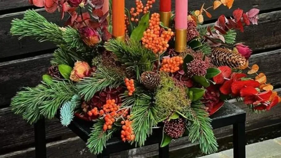 Colorful floral arrangement with candles on table.