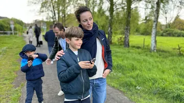 Woman with boy using smartphone in park.