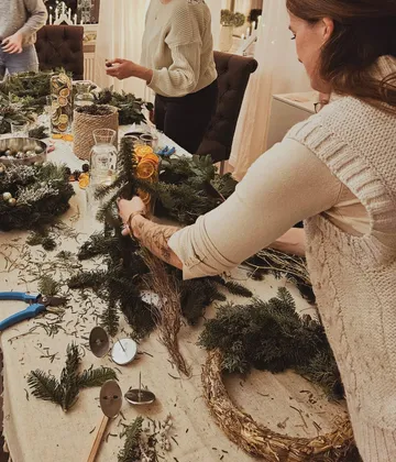 Personen basteln Weihnachtskränze am Tisch.