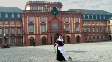 Woman holding lantern in front of palace.