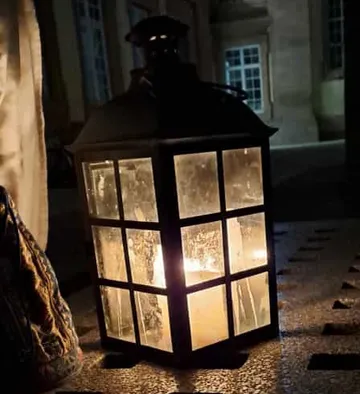 Lantern glowing on a stone surface outdoors.