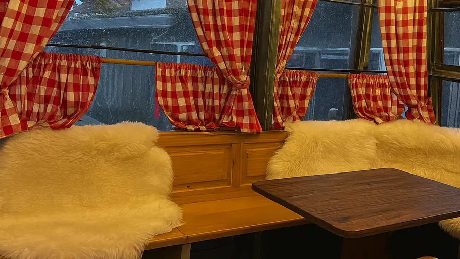 Gemütliche Ecke mit karierten Vorhängen und Fellkissen.