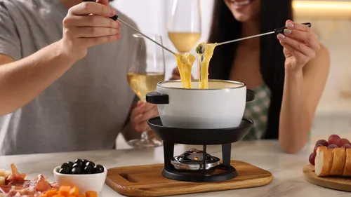 Menschen genießen Käsefondue am Tisch.