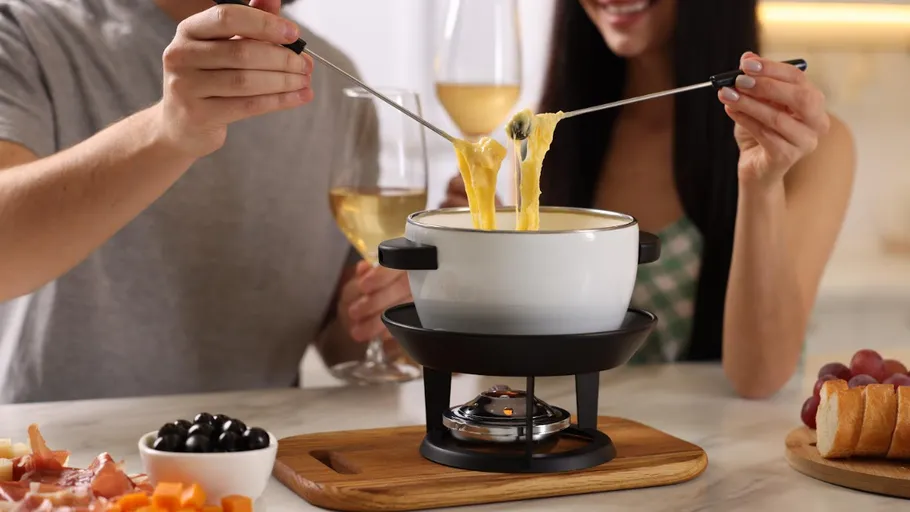 Menschen genießen Käsefondue am Tisch.