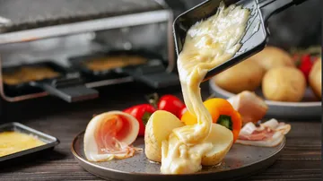 Geschmolzener Käse über Kartoffeln und Gemüse gegossen.