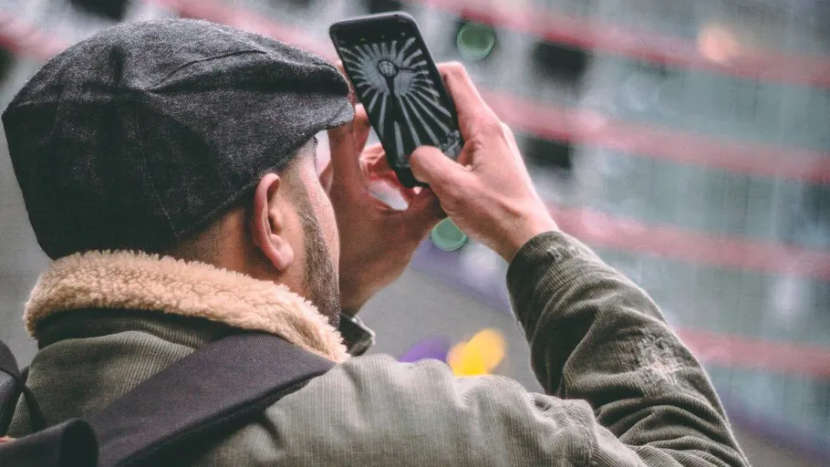 Mann macht Foto mit Smartphone im Freien.