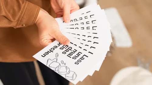 Person holding fanned-out printed cards indoors.