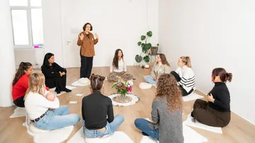 Gruppe sitzt im Kreis während Workshop.