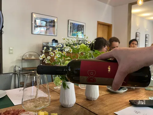 Person gießt Wein in Glas auf Tisch.