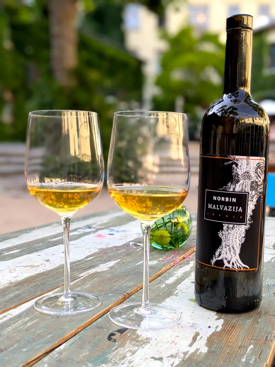 Zwei Weingläser und Flasche auf Holztisch.