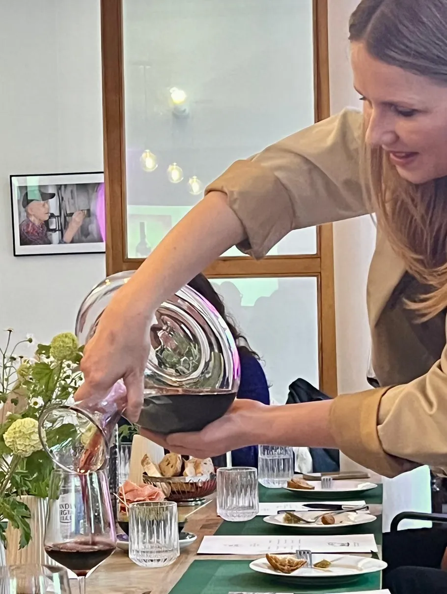 Frau schenkt Rotwein an elegantem Tisch ein.